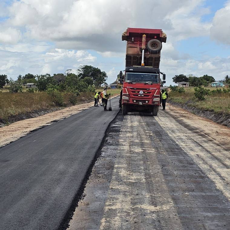 Tipper feeding the paver as fresh asphalt goes down.